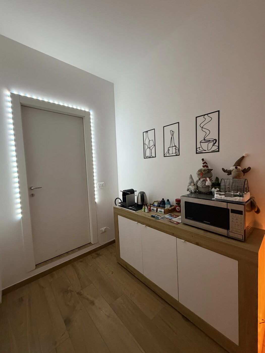 L'ingresso con la porta illuminata a LED e l'angolo colazione: macchina del caffè, bollitore e microonde